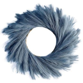 A decorative wreath made of soft, feathery, blue-gray pampas grass. The grasses fan out from the center in a circular pattern, creating a textured, airy appearance. The center of the wreath is open, resembling a soft, fluffy halo.