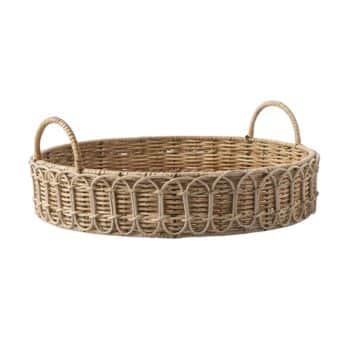 A round, wicker tray with two looped handles on opposite sides. The woven design features intricate patterns around the sides, made from natural-colored rattan material. The tray has a cozy, rustic look suitable for serving or decorative purposes.