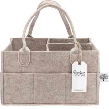 A beige fabric storage caddy featuring multiple compartments and two sturdy handles. A white tag with the text "Parker Baby Co." is attached to one of the handles. An emblem depicting a tree is visible on the side of the caddy.