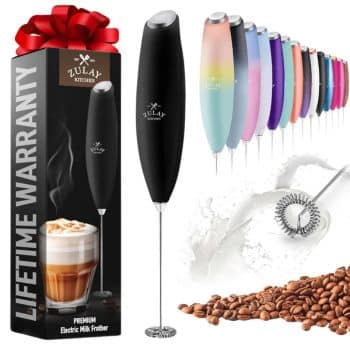 Image of a Zulay Kitchen premium electric milk frother with a lifetime warranty. The main frother is black and next to it is a box with the frother and a coffee image. A variety of colorful frothers are lined up in the background, with coffee beans and milk foam visible.