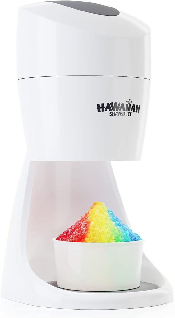 A white Hawaiian Shaved Ice machine dispenses finely shaved ice into a white cup. The ice, similar to vibrant creations found in gourmet ice cream recipes, is colored in a rainbow gradient, starting with red at the top and ending with purple at the base. The machine is sleek and modern-looking.