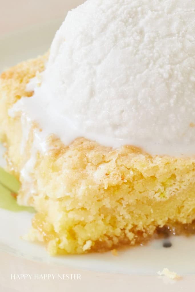 Close-up of a delicious dessert featuring a scoop of vanilla ice cream melting over a piece of crumbly, golden-yellow cake. The cake's texture appears soft and moist, with hints of a sugary crust. The plate underneath the dessert has a faint green tint.