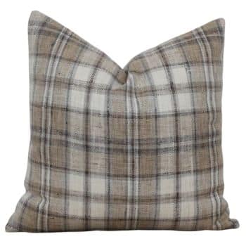 A square throw pillow with a plaid pattern in shades of beige, brown, and white. The design features intersecting lines, creating a classic checkered appearance. The pillow has a slightly pointed top, giving it a cozy and comfortable look.