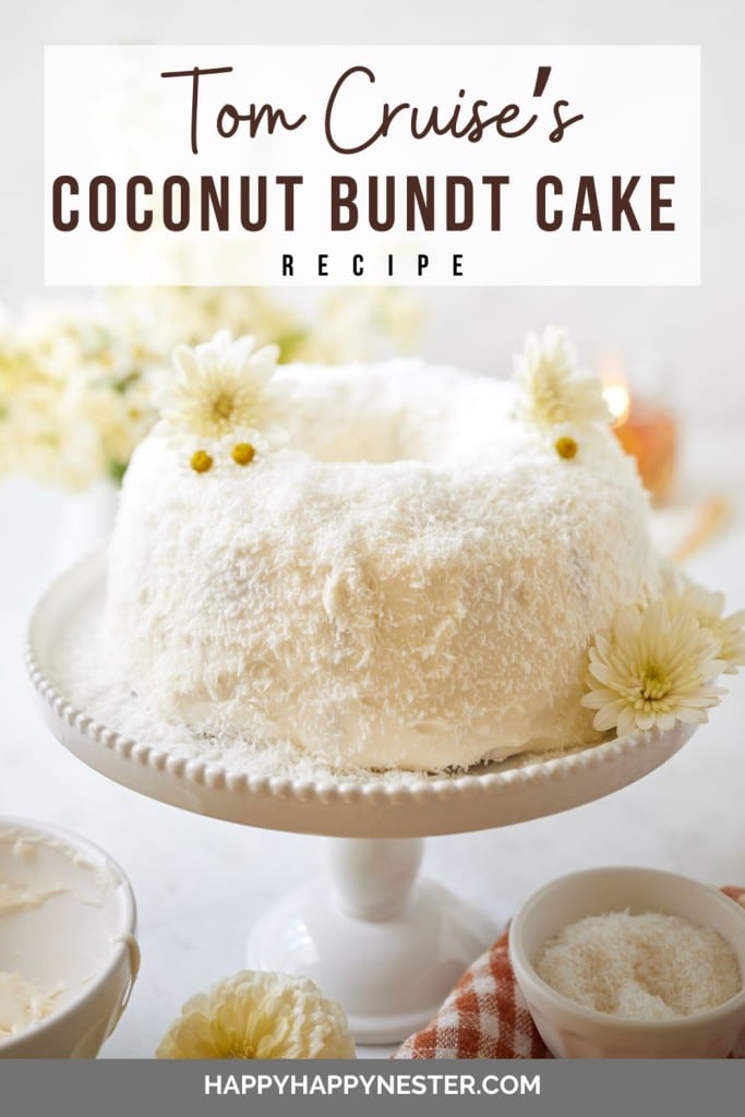 A coconut Bundt cake is displayed on a white pedestal, topped with white frosting and sprinkled with shredded coconut. There are yellow flowers as garnish. The background features white and yellow flowers. Text at the top reads, "Tom Cruise's Coconut Bundt Cake Recipe.