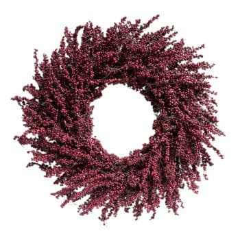 A circular wreath made of densely packed, dark red berry-like clusters. The arrangement is full and lush, with the clusters radiating outward, creating a visually striking and textured appearance. The wreath has an open center and no additional decorations.