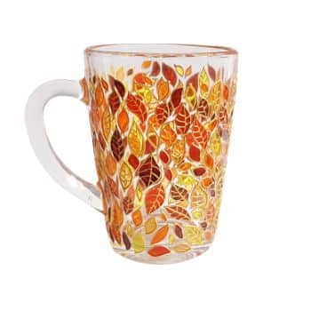 A clear glass mug adorned with a vibrant pattern of autumn leaves in shades of orange, red, and yellow. The design is intricate and covers most of the mug, creating a warm, seasonal feel. The handle is transparent and smooth.