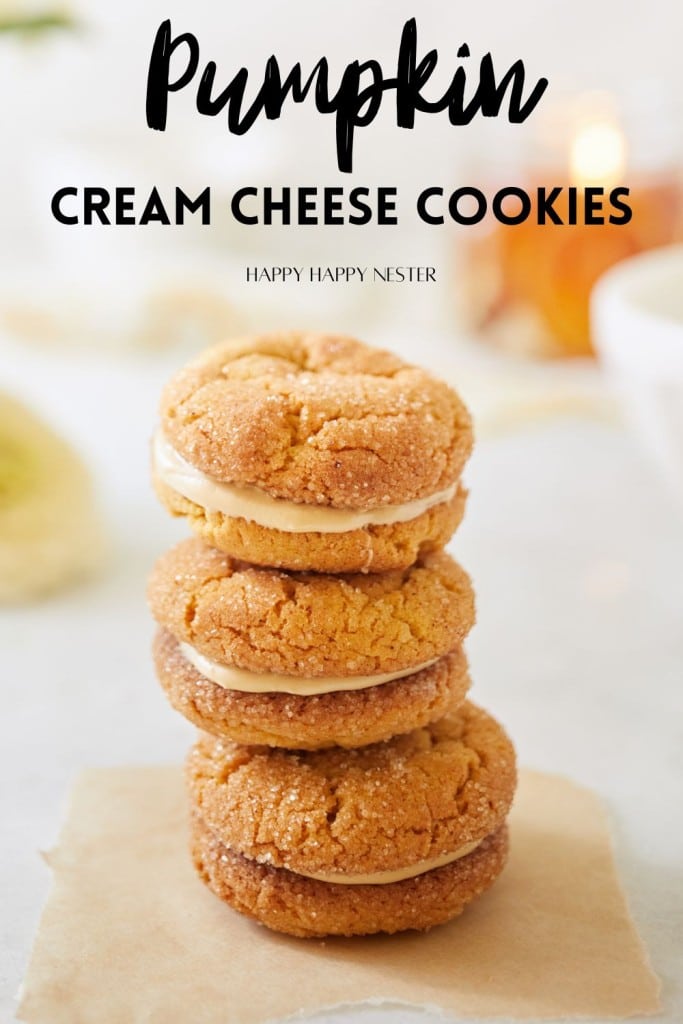 A stack of four pumpkin cream cheese cookies is displayed on parchment paper. The background is softly blurred, highlighting the cookies. The text above reads "Pumpkin Cream Cheese Cookies," captioned by "Happy Happy Nester.