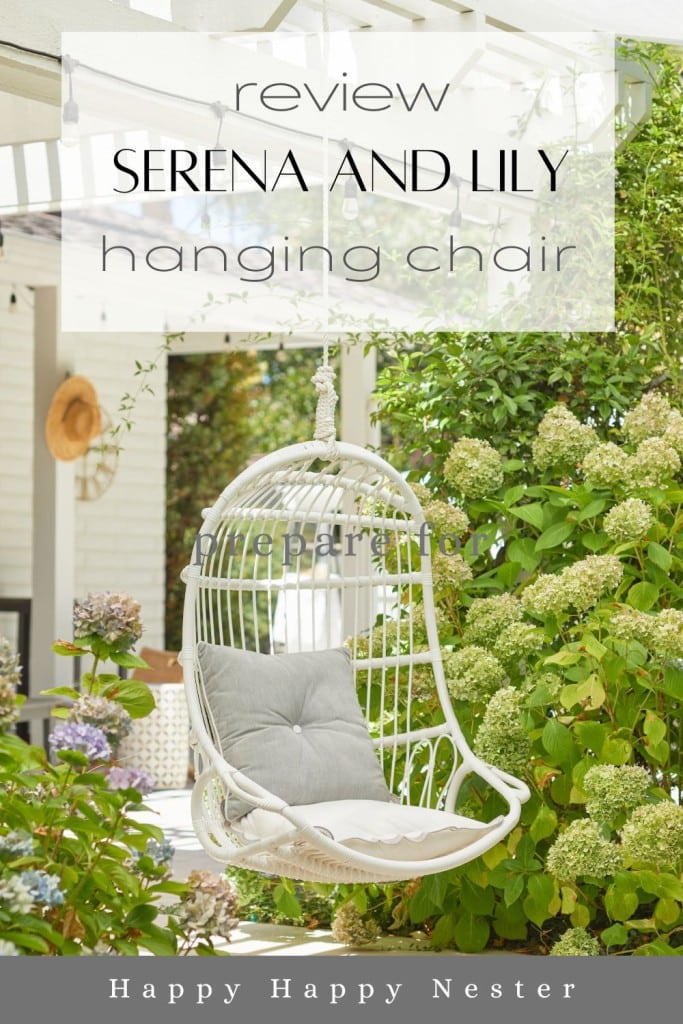 A white wicker hanging chair with light gray cushions is suspended in a lush garden next to blooming hydrangeas. The image is overlaid with text reading, "Review: Serena and Lily hanging chair," and below, "Happy Happy Nester.