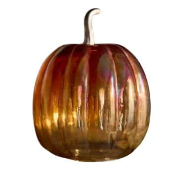 A decorative glass pumpkin with a smooth, glossy surface. The pumpkin features warm, gradient hues of red, orange, and gold, with a shiny, reflective finish. It has a short, curved stem at the top.