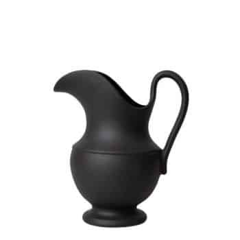 A matte black ceramic pitcher with a bulbous base, a narrow curved spout, and an elegantly curved handle. The design is simple and modern with smooth, clean lines.