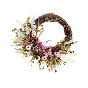 A decorative wreath made of intertwined brown twigs, adorned with various flowers and plants. It features pink and purple blooms, green and brown leaves, and small berries, arranged in a half-circle on the lower part of the wreath.