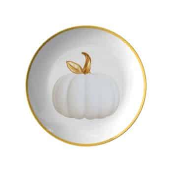 A round white plate with a gold rim featuring a decorative design of a white pumpkin with golden leaves in the center.