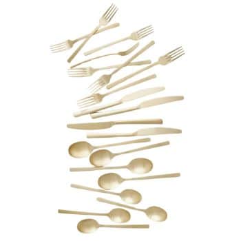 An arrangement of various plastic cutlery pieces including forks, knives, and spoons. The utensils are beige and are scattered in a somewhat organized, diagonal pattern across a plain white background.