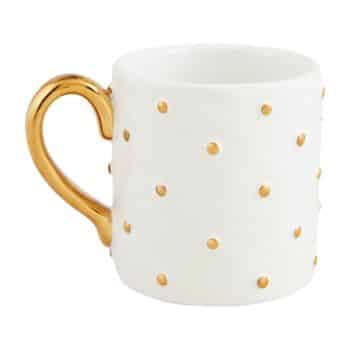 A white ceramic mug with a gold handle and decorated with small gold polka dots evenly distributed across the surface.