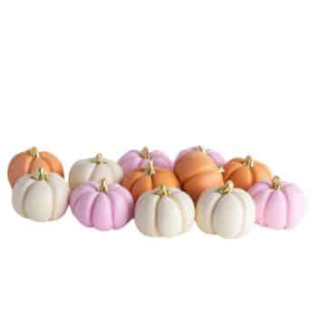 A collection of small decorative pumpkins in pastel colors - white, pink, and orange. They have gold stems and are arranged closely together on a plain white background.