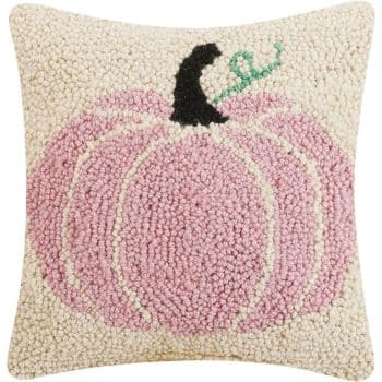 Square cushion with a hooked design of a pink pumpkin with a black stem on a light beige background. The pumpkin has a green curly leaf attached to the stem. The texture appears soft with small, raised loops creating the design.