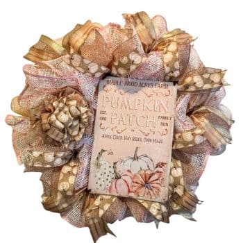 A decorative wreath made of various brown and beige ribbons with a sign in the center. The sign reads "Maple Wood Acres Farm Pumpkin Patch" and features illustrations of pumpkins, leaves, and text about farm activities like apple cider, hay rides, and a corn maze.