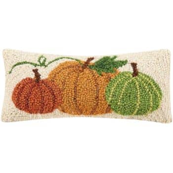 A rectangular decorative pillow, perfect for festive fall decor, features a woven design of three pumpkins in shades of orange, green, and brown set against a beige background. The texture suggests a handcrafted, rustic look.