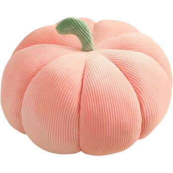 A round, plush cushion shaped like a pumpkin, with soft, segmented sections. The cushion is light pink and has a green stem protruding from the top, resembling a pumpkin's stem. The cushion has a textured surface, resembling ribbed fabric.