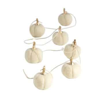 String of white artificial pumpkins against a white background.