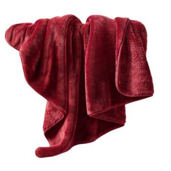 A soft, plush red blanket is draped casually over an unseen surface. The fabric appears luxurious and cozy, with a rich, deep red color and a slightly shiny texture.