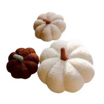 Three cozy, plush pumpkins are displayed against a plain white background. The pumpkins are various sizes and colors, including deep orange, light beige, and off-white. Each features a textured fabric surface and realistic stems—perfect fall decor ideas for adding warmth to any space.