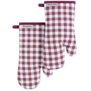 A pair of KitchenAid oven mitts with a red and white checkered pattern, perfect for handling hot dishes during your autumn recipes. Each mitt includes a small fabric loop for hanging, located at the cuff. The design features a classic, quilt-like look.