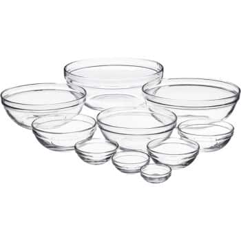 A collection of clear glass mixing bowls of various sizes is arranged in a semi-circle, with the largest bowls at the back and the smallest bowls at the front. The bowls are clean and empty, showing a transparent and reflective surface, ready to be filled with your favorite autumn recipes.