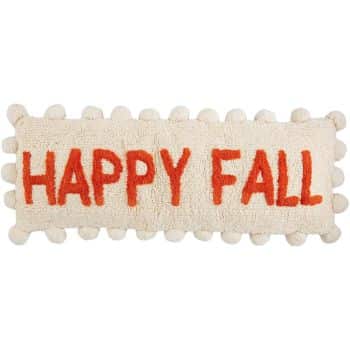 A rectangular, cream-colored rug with "HAPPY FALL" written in orange-red letters across the center. The edges of the rug are decorated with round, pompom-like tassels, making it a charming addition to your fall decor ideas.