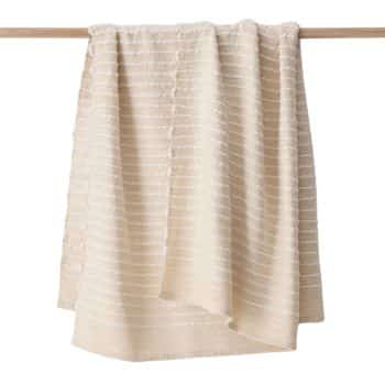 A beige towel with horizontal white stripes hangs draped over a wooden rod.