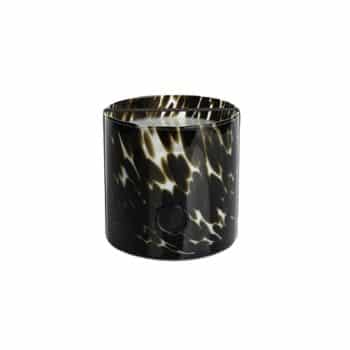 A cylindrical candle with a black and white tortoiseshell pattern on the glass container. The candle has a flat, smooth surface and is unlit.