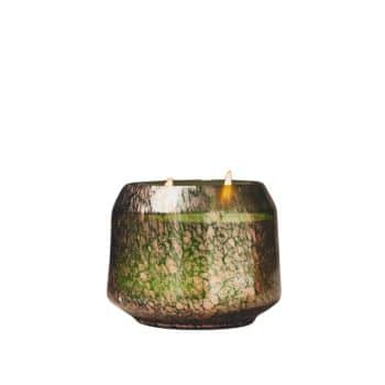 A small round candle with two lit wicks, set in a textured green and black glass holder.