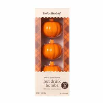 A box of three pumpkin-shaped white chocolate hot drink bombs with mini marshmallows. The packaging is cream-colored with a plaid orange pattern and labeled "Favorite Day" and "hot drink bombs.