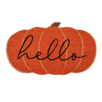 A doormat shaped like a pumpkin with the word "hello" written in black cursive across it. The doormat is orange, resembling a classic fall pumpkin.