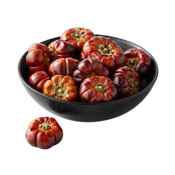 A black bowl filled with glossy, deep red miniature pumpkins. One pumpkin is placed beside the bowl. The pumpkins have a shiny surface and prominent ridges, sitting on a plain white background.