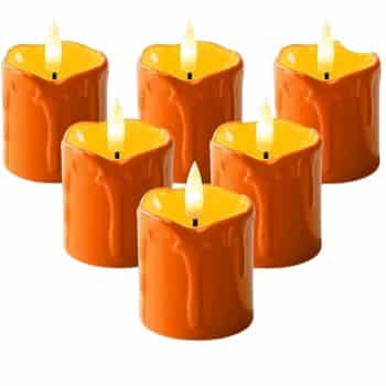 Six orange candles with melted wax details are arranged in two rows on a white background, each with a small, lit flame at the center—perfect as front door decor for fall.