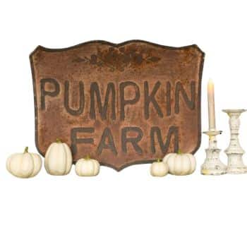 A rustic "Pumpkin Farm" sign is displayed with several small white pumpkins in front. Two decorative candlesticks, one with a lit candle, are arranged on the right side.