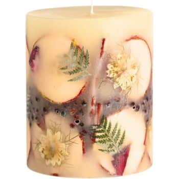 A decorative candle featuring embedded dried flowers and green leaves. The wax is a creamy beige color, and the intricate floral design adds an elegant touch to the cylindrical shape.