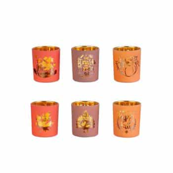 Six small candle holders in two rows with autumn-themed designs and gold interiors. The colors include orange, red, and purple, each featuring seasonal motifs like leaves and pumpkins.