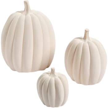 Three white ceramic pumpkins of varying sizes are grouped together, showcasing vertical ridges and realistic stems. This simple yet elegant decoration embodies the essence of easy pumpkin crafts, adding a touch of charm to any space.