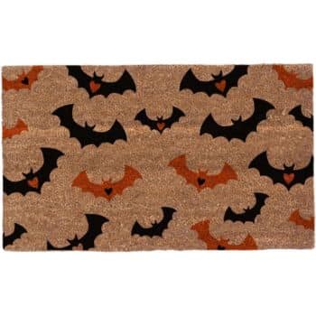 A doormat featuring a design of black and orange bats with small hearts on their bodies scattered across a brown background.