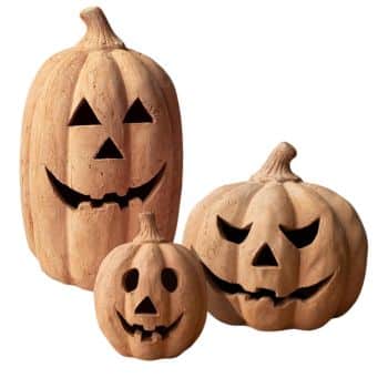 Three carved pumpkins with traditional jack-o’-lantern faces—triangle eyes and jagged mouths—are grouped together, varying in size and height. Perfect as front door decor for fall, they bring festive charm to any entryway.