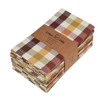 A stack of folded, multicolored checkered fabric pieces, wrapped with a brown paper band labeled "Wren Table." The colors include shades of brown, yellow, white, and green.