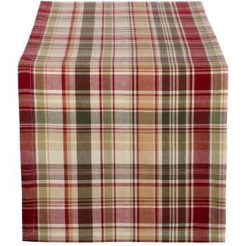 A table runner with a plaid pattern featuring red, green, beige, and white colors. The fabric is neatly draped over the edge of the table, creating a cozy and festive appearance.