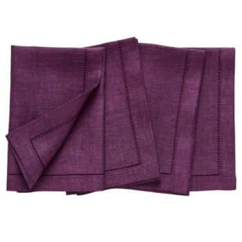 A set of folded dark purple linen napkins with hemstitch detailing along the edges, neatly arranged.