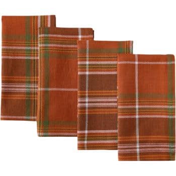 Four folded plaid napkins in shades of orange, brown, and green, featuring a white grid pattern, are neatly arranged.