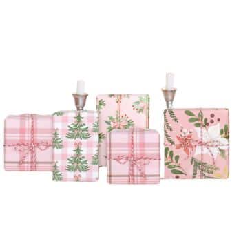 Four gift boxes wrapped in pink and green plaid and floral paper, tied with pink bows. Two tall boxes have faux candles on top. The design features holiday themes with trees and botanical elements.