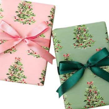 Two gift boxes wrapped in festive paper with Christmas tree designs. One is wrapped in pink paper with a pink ribbon, and the other in green paper with a green ribbon, both adorned with bows.