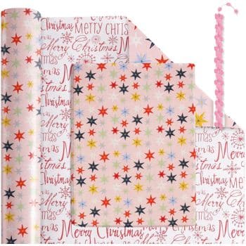 A roll of festive wrapping paper featuring "Merry Christmas" text and multicolored stars. The paper is partially unrolled, showing both designs. A pink gift ribbon is also visible next to the paper.