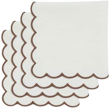 Four neatly stacked white napkins with scalloped edges outlined in brown.